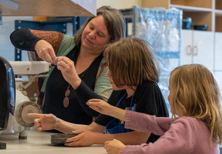 Kids in the ceramics studio, helped by an adult