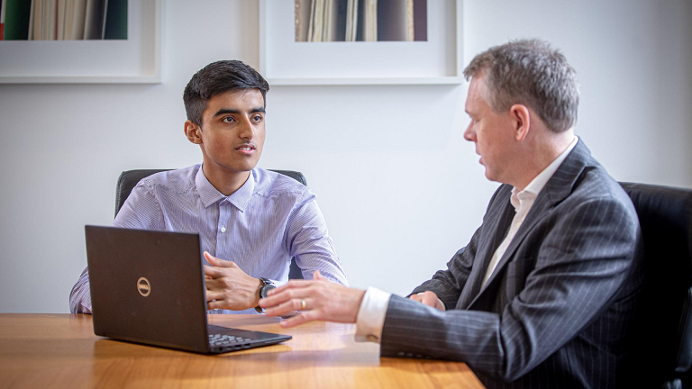 A student and mentor sit in front of a laptop