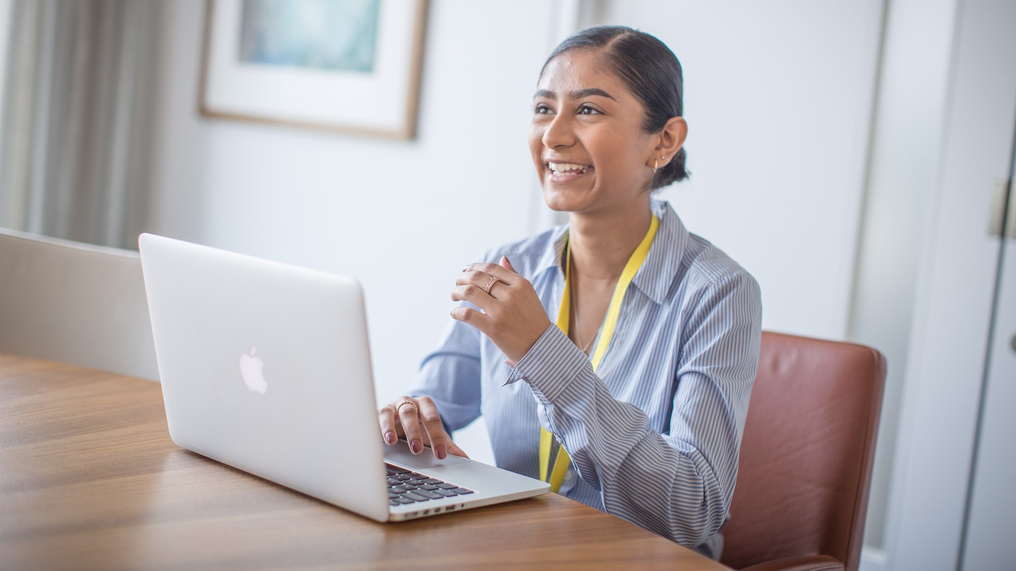 A student laughs from behind a laptop